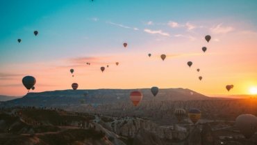 hot air balloons flying over the mountains