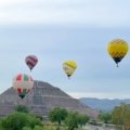 a group of hot air balloons flying over a pyramid