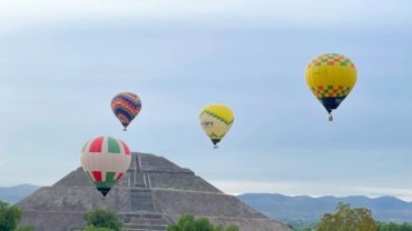 a group of hot air balloons flying over a pyramid