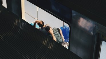 a man sitting on top of a train next to a window
