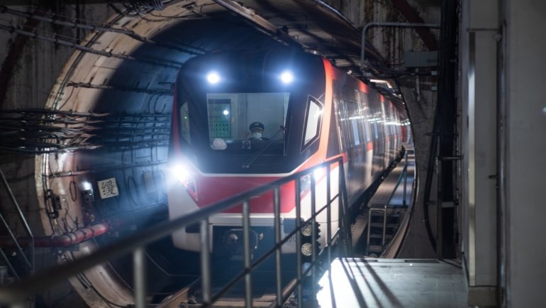 a train traveling through a tunnel next to a loading platform