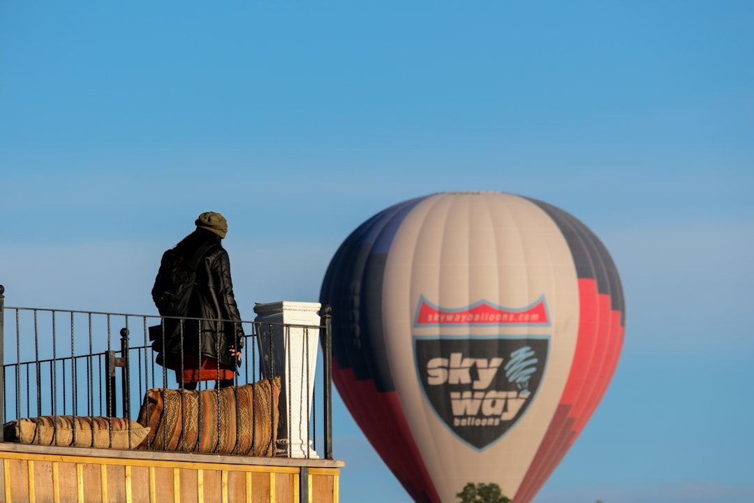 a man standing on a balcony next to a hot air balloon