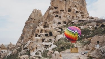 a hot air balloon flying over a rocky mountain