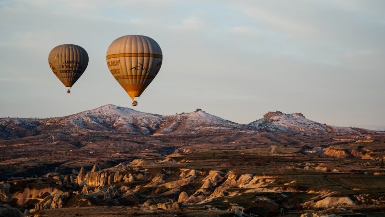 hot air balloon flying over the mountains during daytime